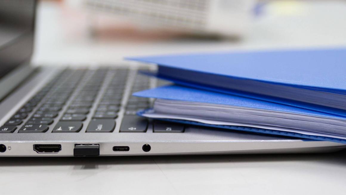 Files and paperwork sitting on top of a laptop keyboard.