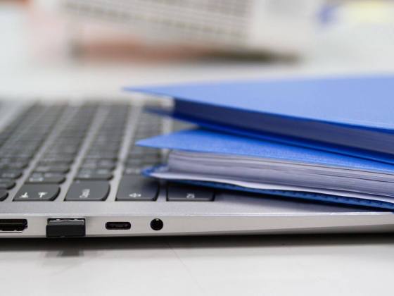 Files and paperwork sitting on top of a laptop keyboard.