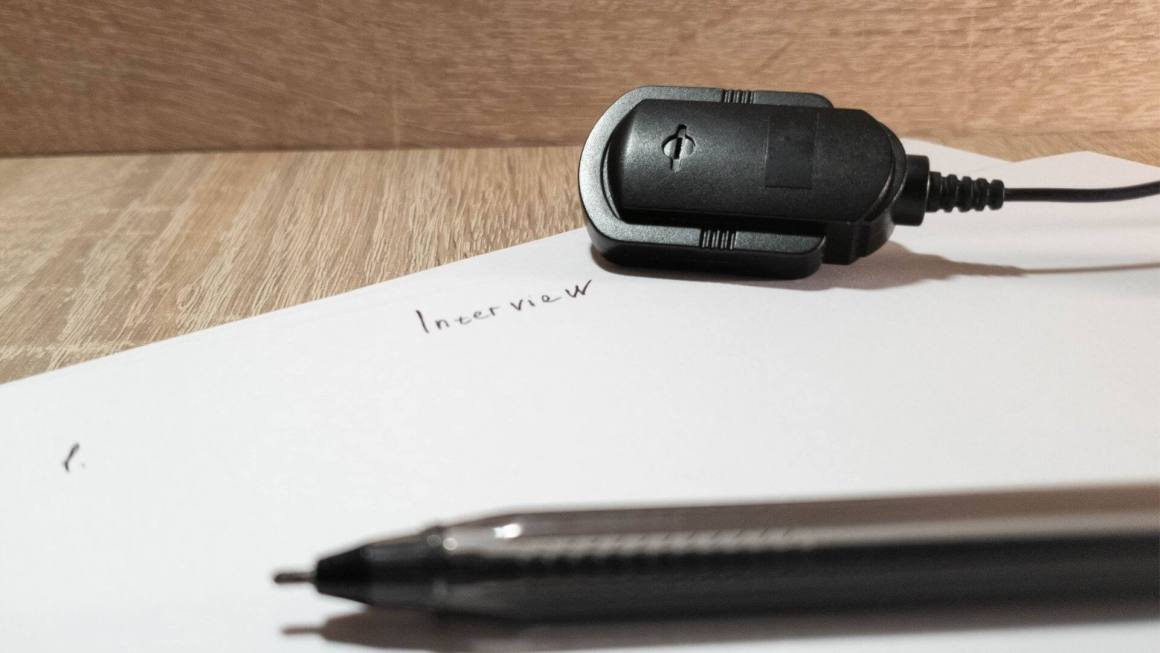 A piece of paper, pen, and microphone lie waiting for an interview to begin.