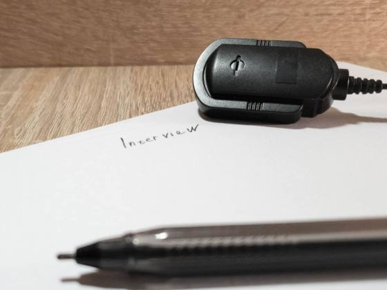 A piece of paper, pen, and microphone lie waiting for an interview to begin.