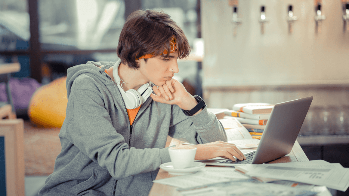 Student working on his research paper on a laptop.