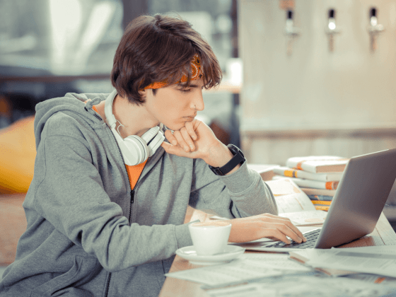 Student working on his research paper on a laptop.