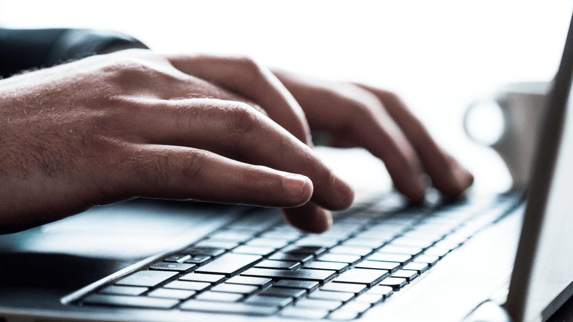 Close up shot of hands typing on a laptop keyboard