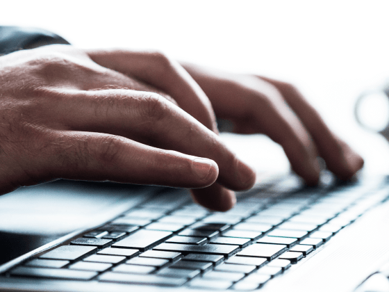 Close up shot of hands typing on a laptop keyboard